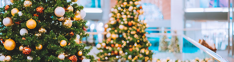 holiday installs consisting of Christmas trees decked in gold and red baubles surrounded by garland-covered handrails