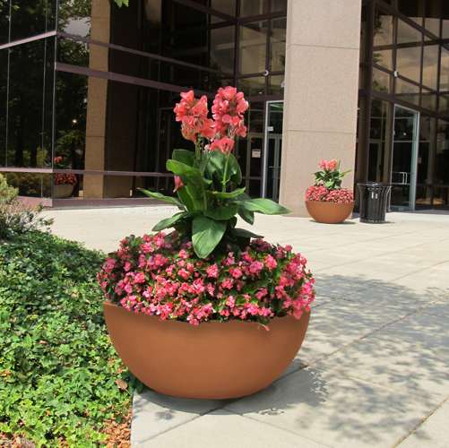 outdoor flat bottom plant container with pink flowers installed outside of office building