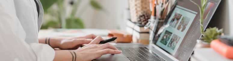 a woman in a white shirt working on her laptop with plants nearby