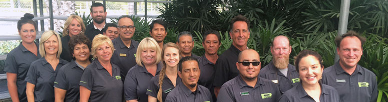 An interiorscape team standing together and smiling in a greenhouse-like setting