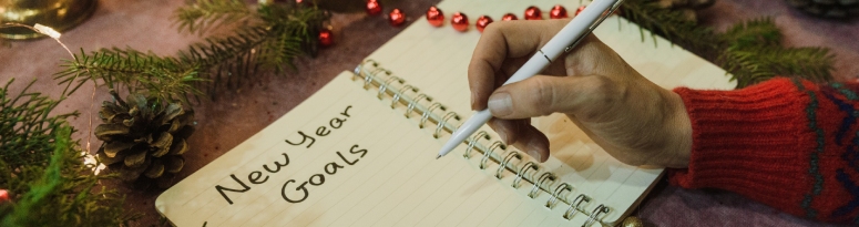 an employee jotting down New Year's goals in a notebook